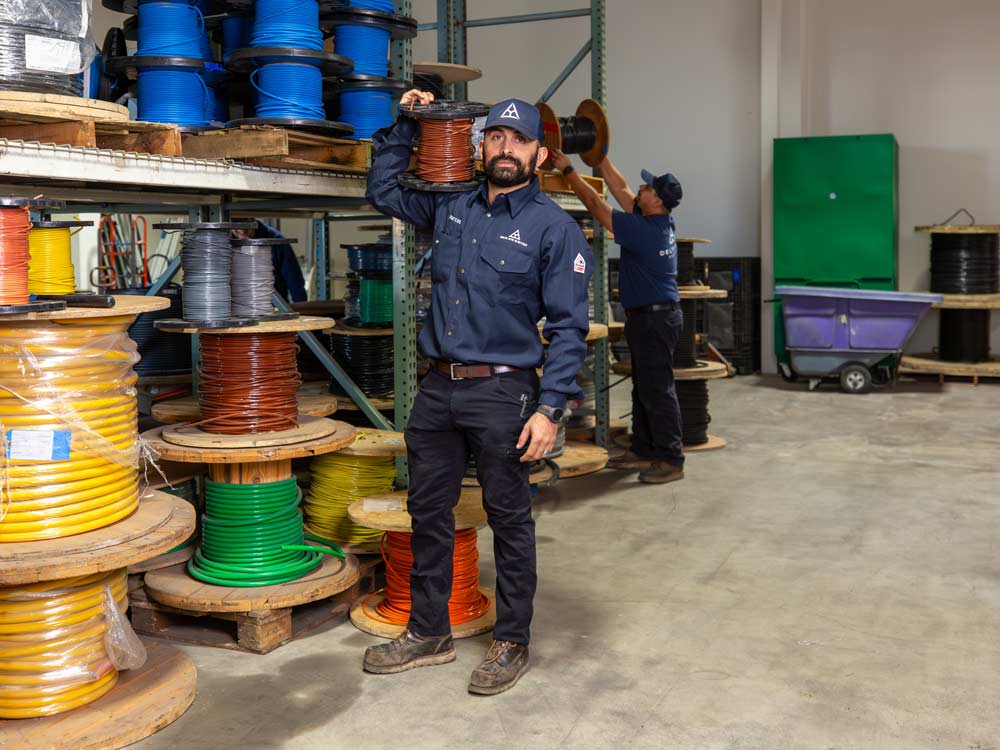 A man standing in a warehouse full of spools of wire.